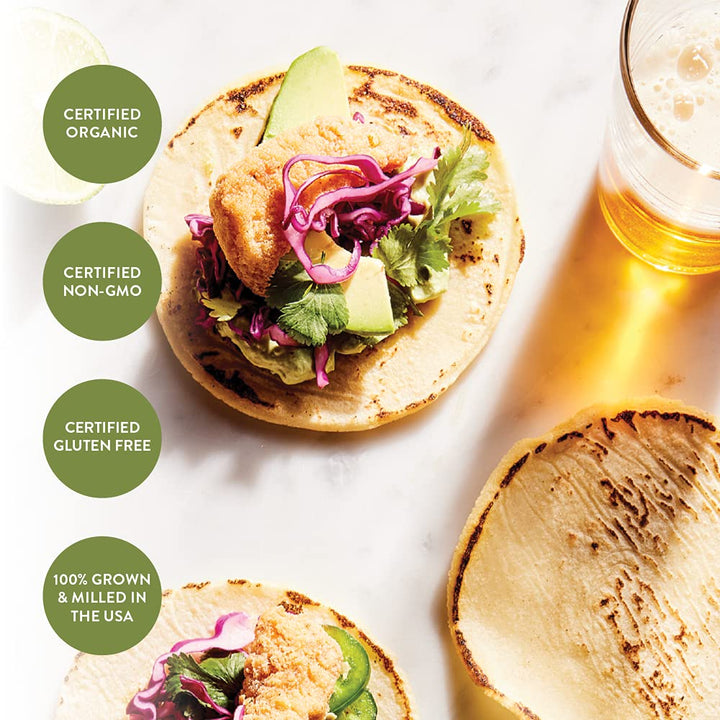 Tortilla with toppings and a glass of beer on a white surface, with certification labels around.