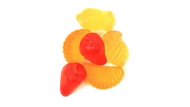 Colorful gummy candies shaped like fruit on a white background