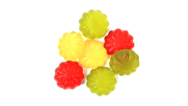 Colorful vegan gummy flower candies on a white background