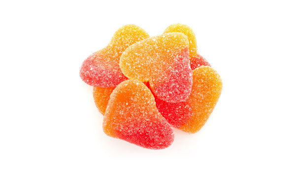 Colorful soft peach gummy candy hearts on a white background