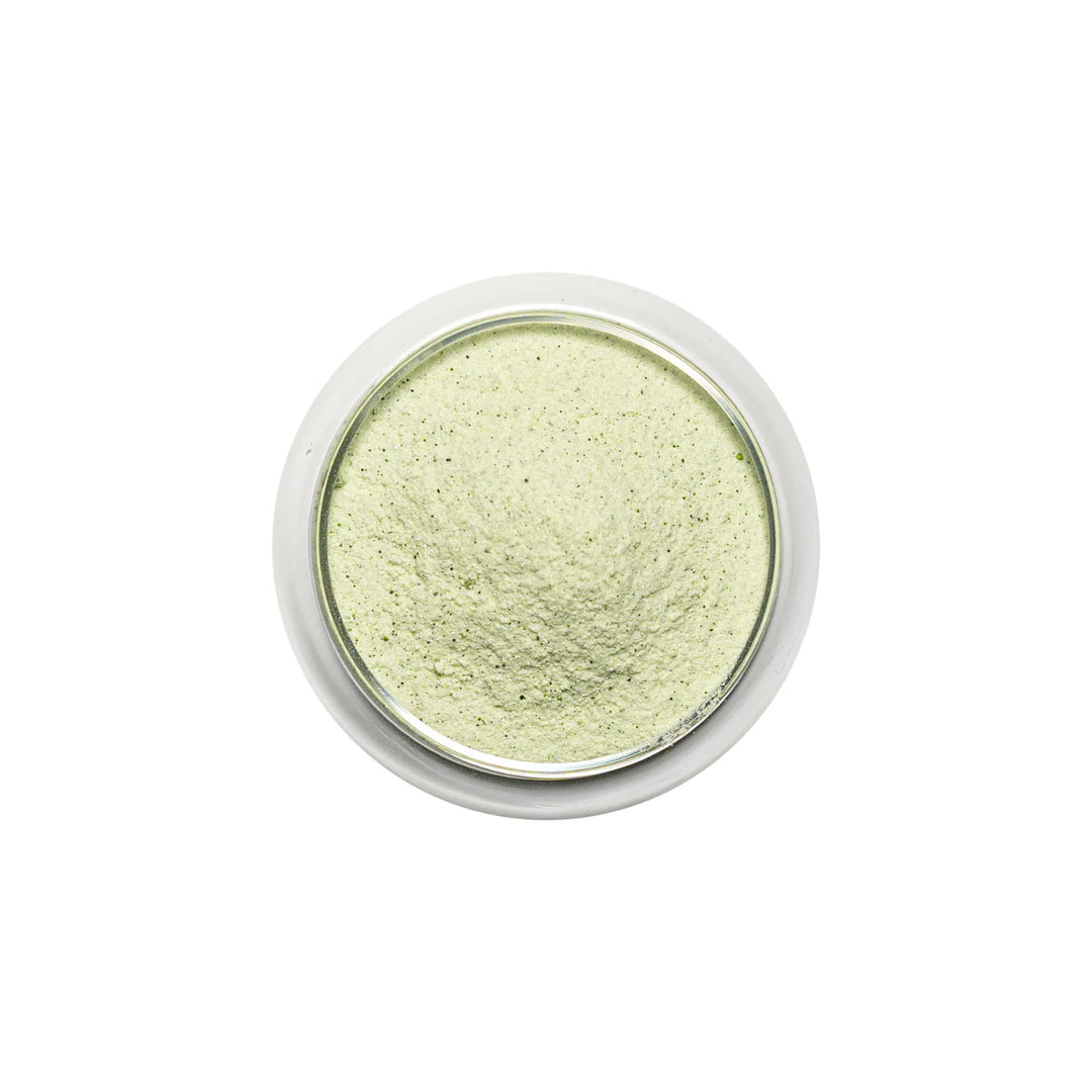 Green pandan powder in a small round container on a white background