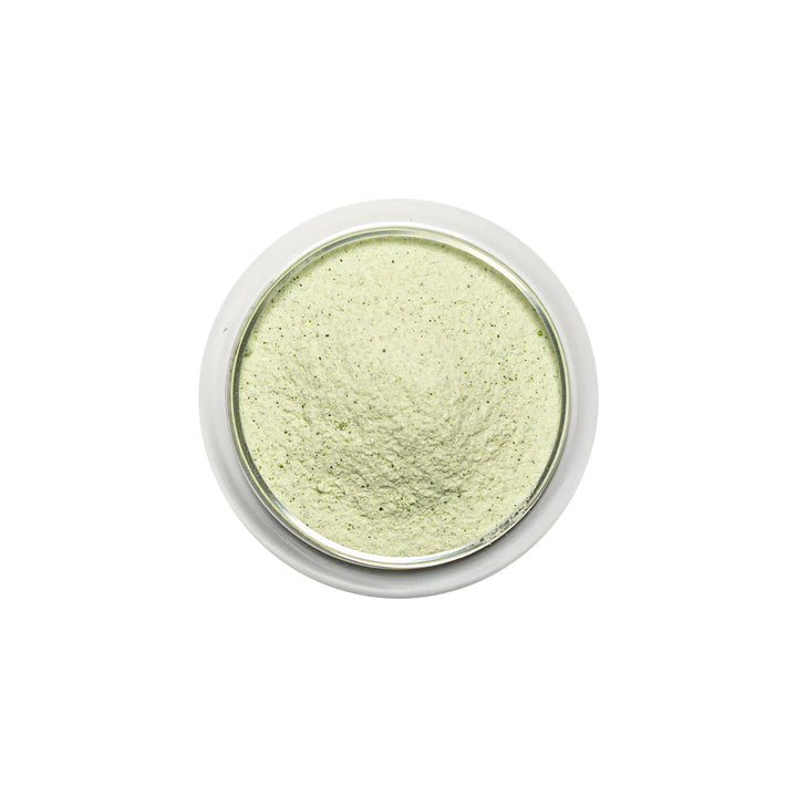 Green pandan powder in a small round container on a white background
