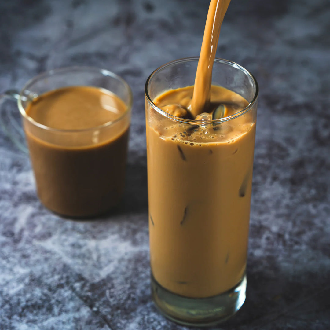 Glass of iced coffee with a pitcher of coffee on a dark textured surface