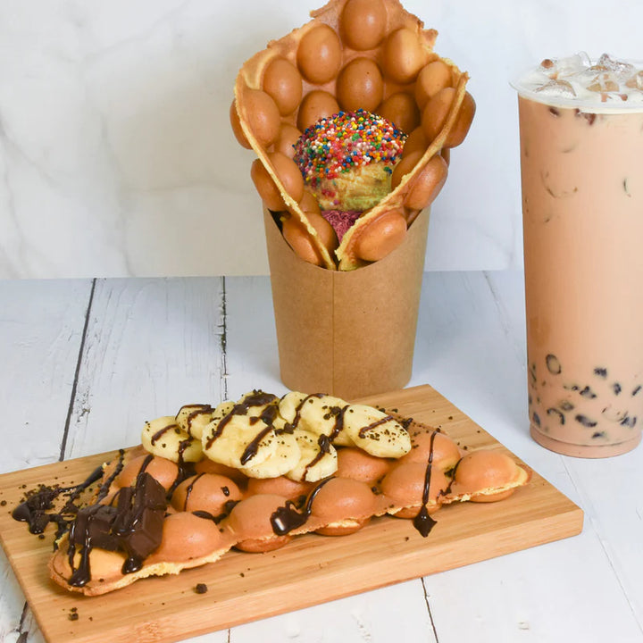 Waffle cone with ice cream and bubble tea on a wooden board