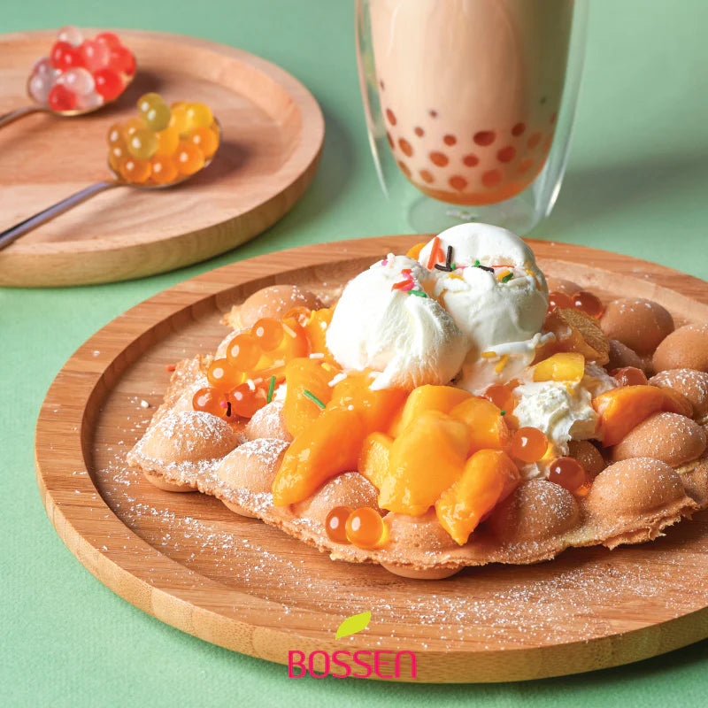 Dessert with ice cream and fruit on a wooden plate with a glass of bubble tea in the background.