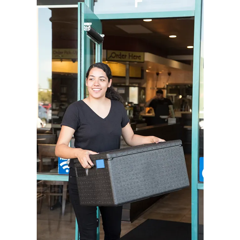 Person holding a gray box in front of a store entrance