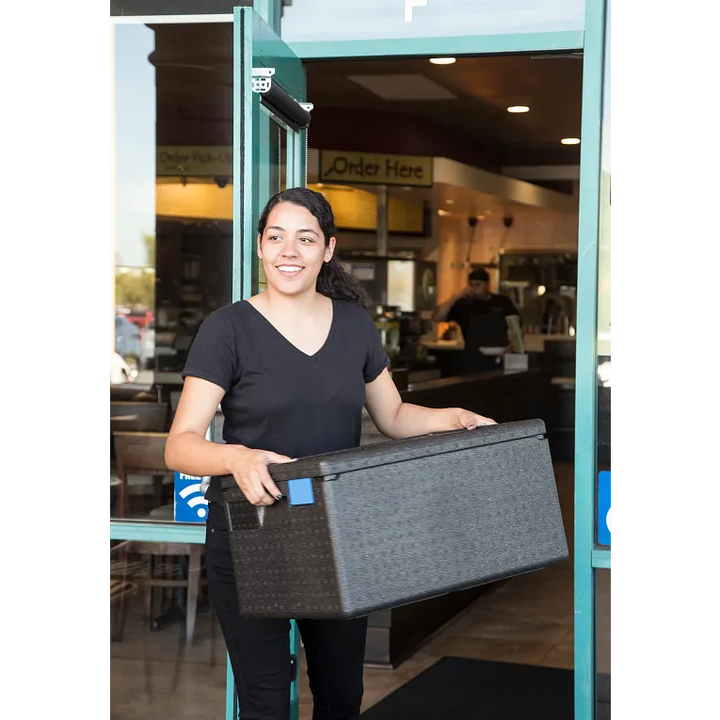 Person holding a gray box in front of a store entrance