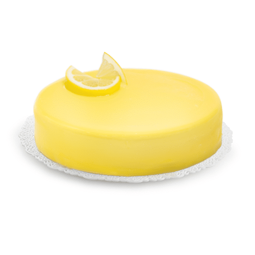 Yellow cake coated with Rubicone lemon glaze garnished with a lemon wedge on top on a white background
