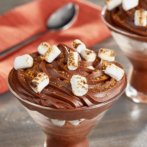 Chocolate dessert with marshmallows in a glass bowl on a wooden surface.