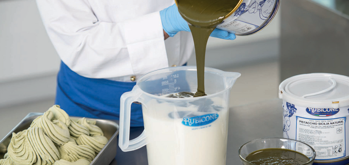 Person pouring pistachio paste from a container into a Rubicone base