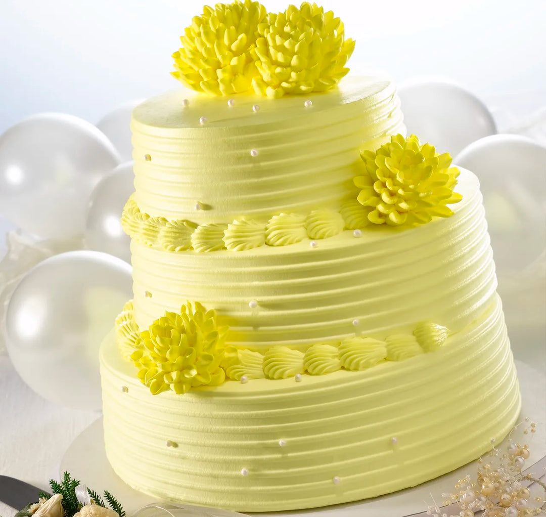 Two-tiered yellow cake with decorative flowers on a white background