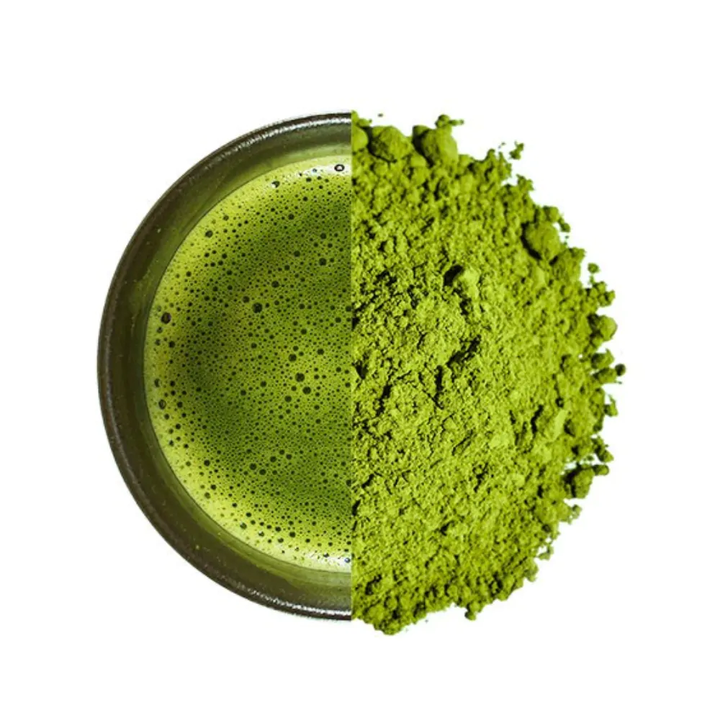 Matcha green tea powder and frothy matcha beverage in a bowl on a white background
