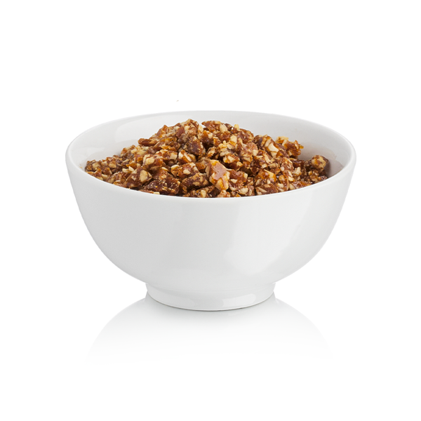 White bowl filled with rubicone crunchy chopped hazelnuts on a white background