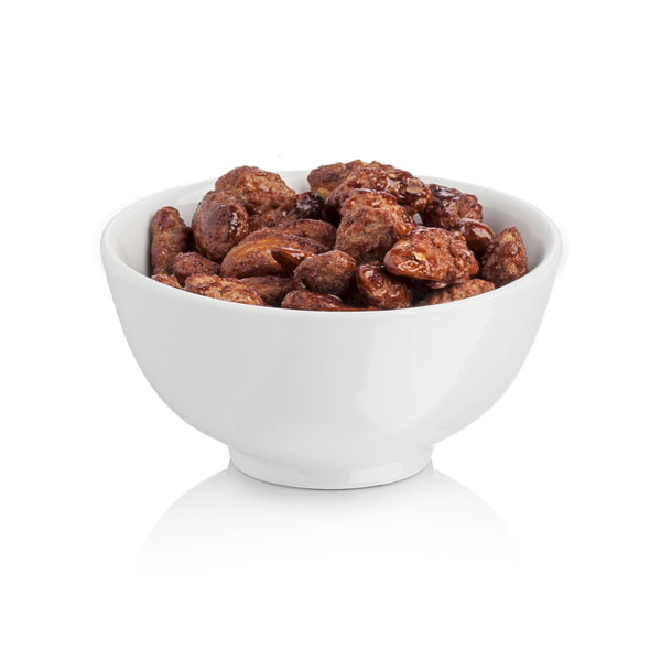 White bowl filled with whole almonds with a praline coating on a white background