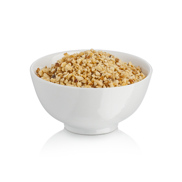 White bowl filled with chopped hazelnut grains on a white background