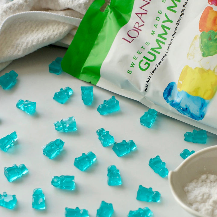 Blue gummy bears with a green and white package on a light surface. lorann, fun foods canada