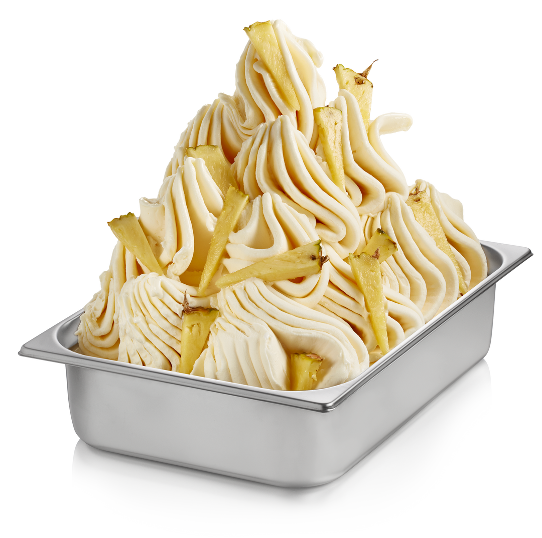 Pineapple gelato in a wide stainless steel pan with pineapple pieces made with Rubicone Pineapple Ready Base