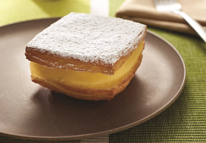 Pastry with powdered sugar on a brown plate Puratos Canada