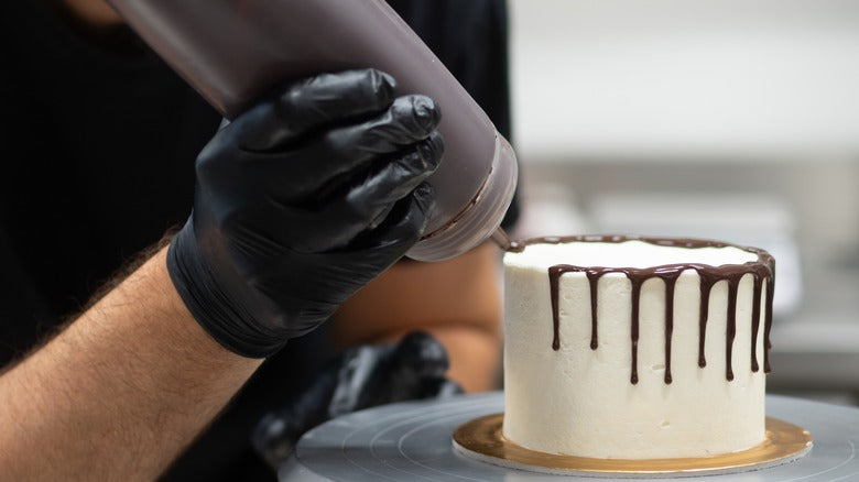 Person decorating a cake with chocolate drizzle in Canada provided by Rubicone Canada